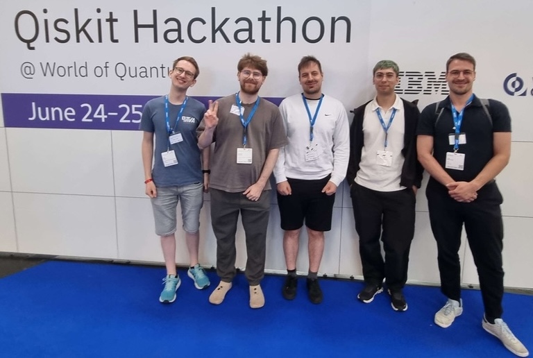 Five people standing in front of a Qiskit Hackathon sign at World of Quantum.